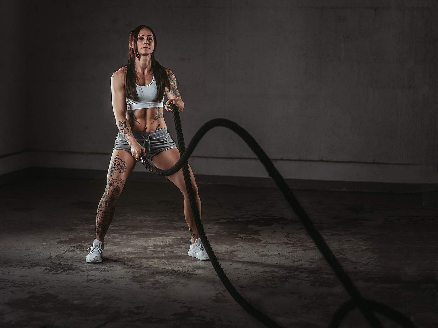 Sportlerin beim Training mit Battle Ropes in einer Halle